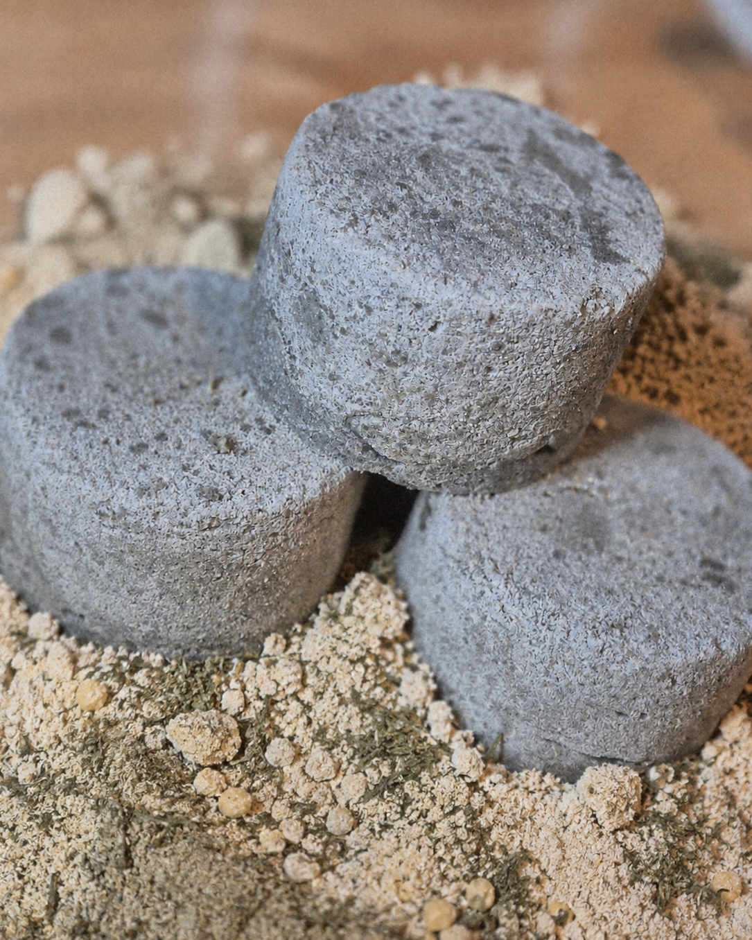 Shampoing solide purifiant – trois pains gris posés sur de la poudre d'argile